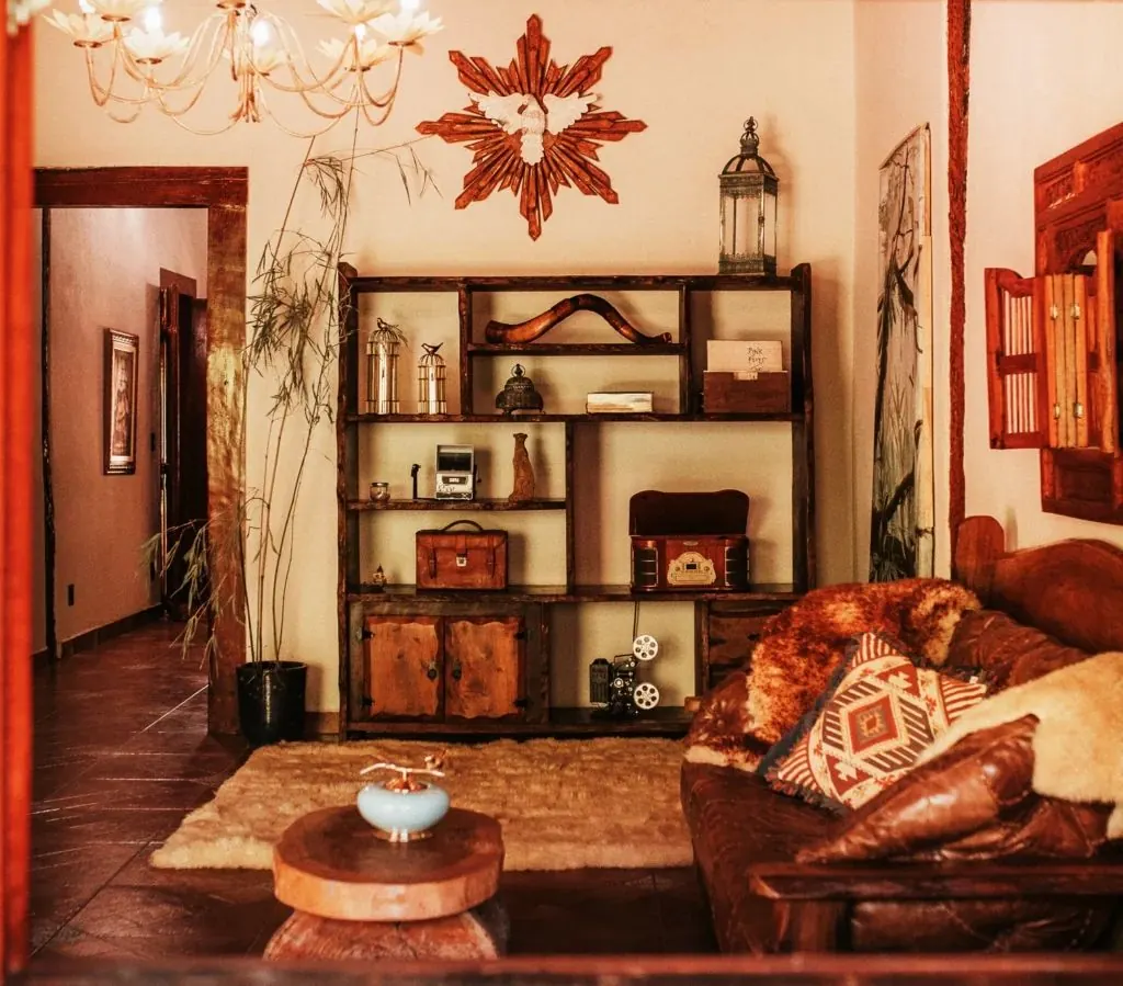 Interior da sede da Fazenda Bosque Belo Baguá, com estante de madeira, lustre e sofá de couro